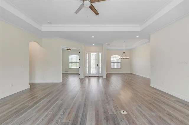 a view of an empty room and kitchen view with wooden floor and a ceiling fan