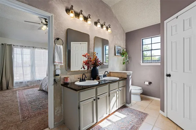 a bathroom with a granite countertop sink a toilet and a mirror