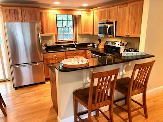 136 East Osterville Road Osterville, MA 02655 - Photo 11 of 22 a kitchen with stainless steel appliances granite countertop a refrigerator a stove a sink a dining table and chairs with wooden floor
