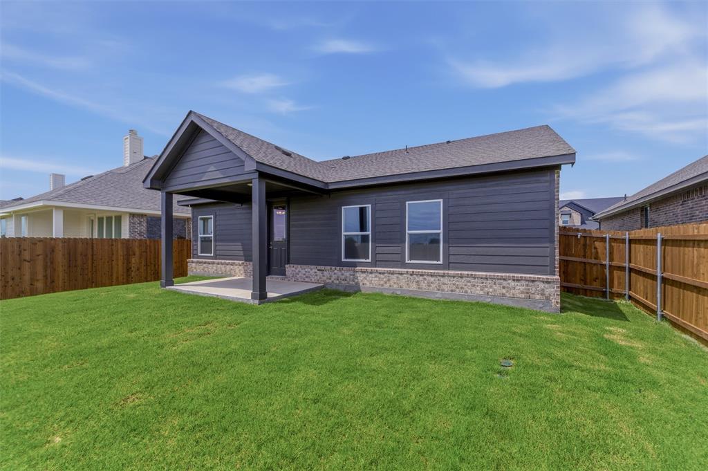 3504 Helena Street Gainesville, TX 76240 - Photo 18 of 19 Expansive backyard featuring a covered patio, dark gray siding, brick wainscoting, and a full wood fence