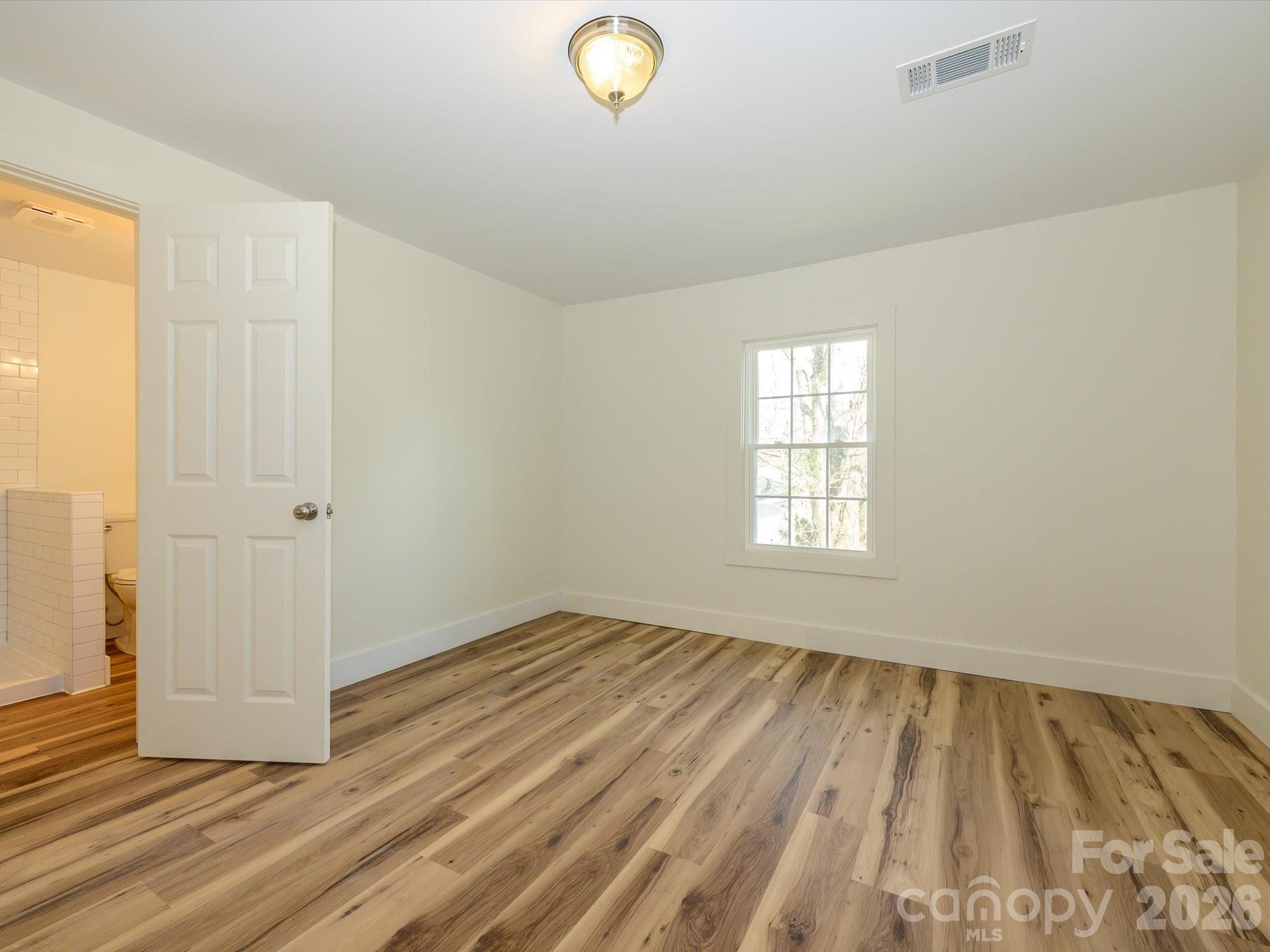 156 Hartsell School Road Southwest Concord, NC 28027 - Photo 15 of 28 an empty room with wooden floor and windows
