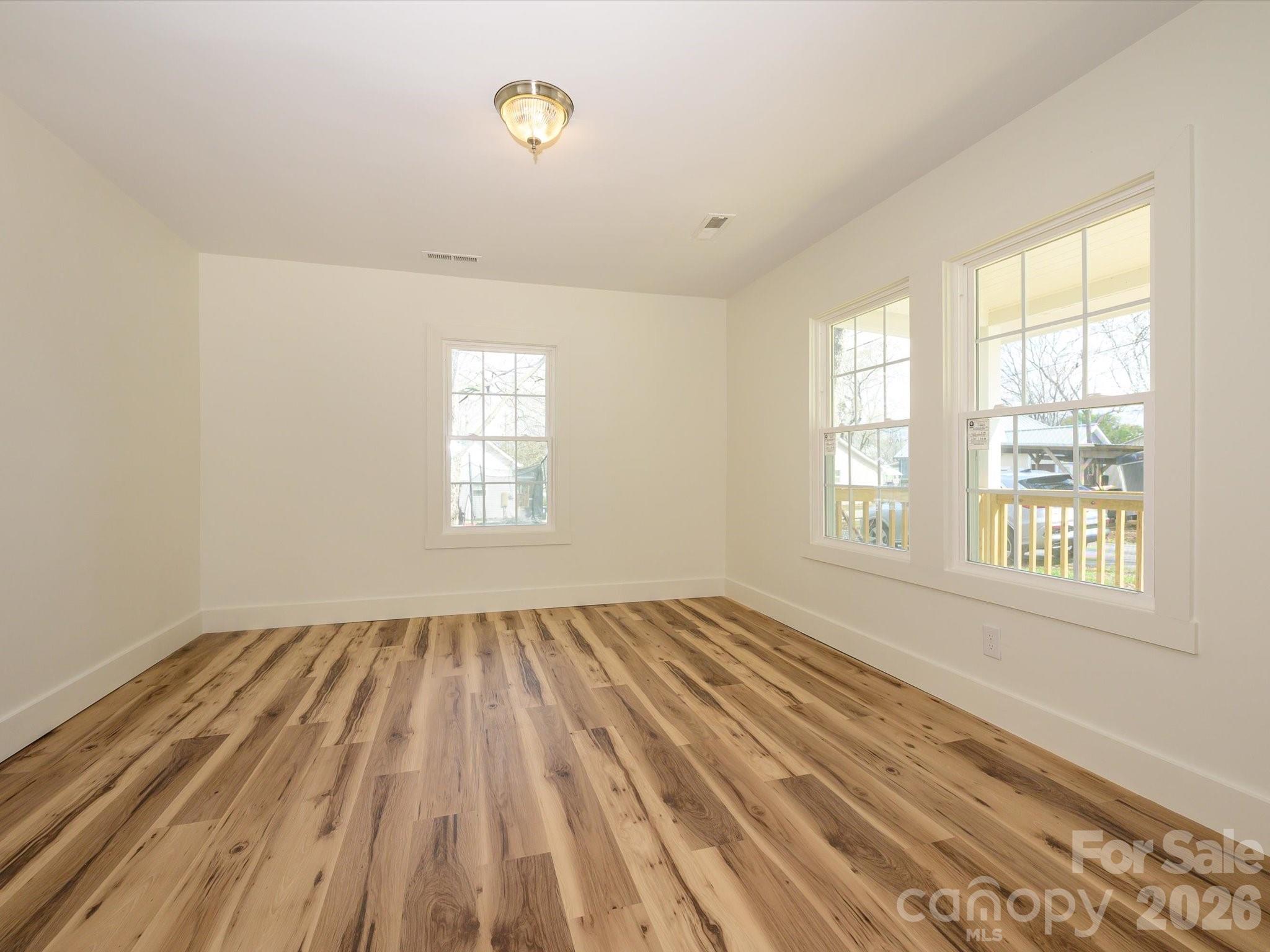 156 Hartsell School Road Southwest Concord, NC 28027 - Photo 19 of 28 an empty room with wooden floor and windows