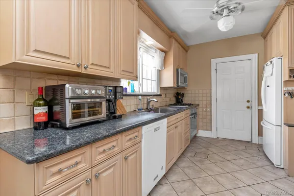 a kitchen with stainless steel appliances granite countertop a sink dishwasher a refrigerator and cabinets
