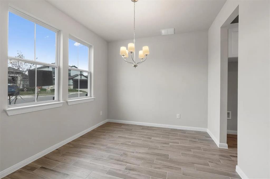 332 Stellar Wind Drive Georgetown, TX 78628 - Photo 10 of 29 A refined dining space features wood-look tile flooring, abundant natural light, and a classic chandelier.