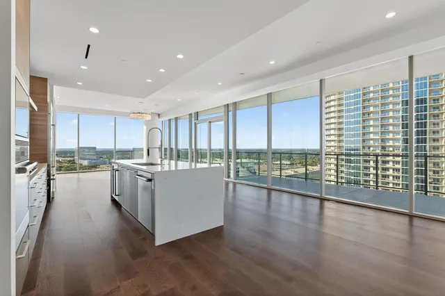 a large white kitchen with a large window a sink and stainless steel appliances