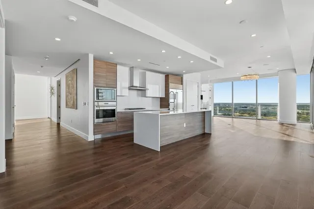 a large kitchen with stainless steel appliances refrigerator a stove top oven with wooden floors