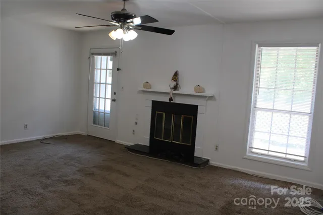a view of an empty room with a fireplace and wooden floor