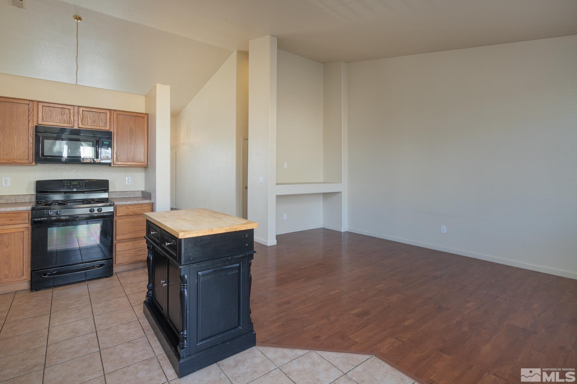 8987 Sorcha Street Reno, NV 89506 - Photo 7 of 29 a kitchen with kitchen island a stove a microwave and a refrigerator