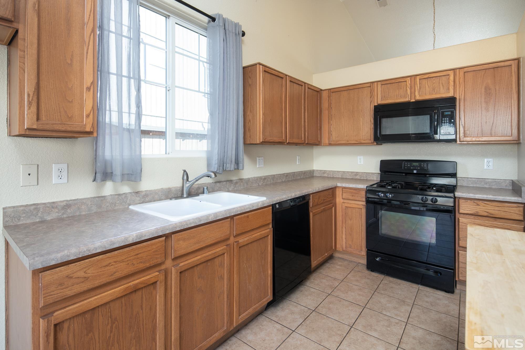 8987 Sorcha Street Reno, NV 89506 - Photo 9 of 29 a kitchen with stainless steel appliances granite countertop a sink dishwasher stove and refrigerator