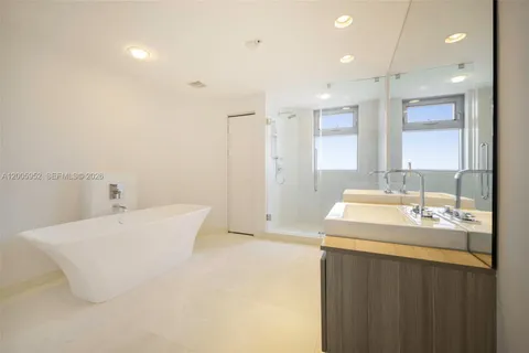a bathroom with a bathtub shower sink vanity and mirror