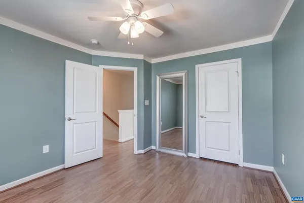 an empty room with wooden floor and ceiling fan