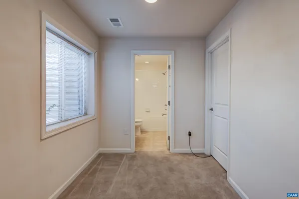 a view of an empty room with window and closet area