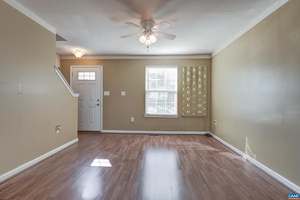 an empty room with wooden floor chandelier fan and windows