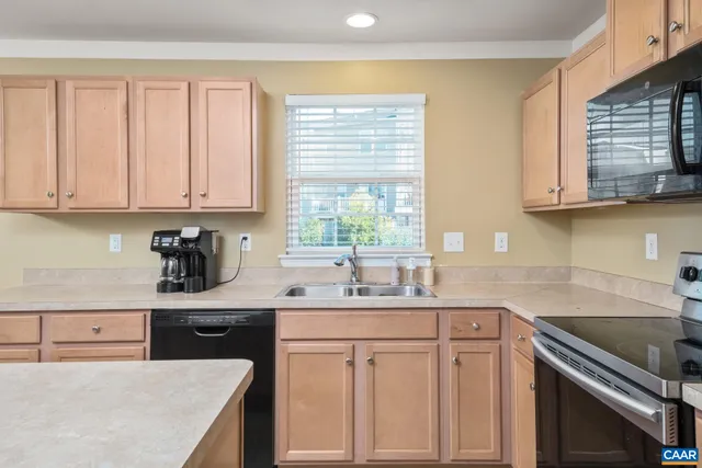 a kitchen with granite countertop a sink dishwasher stove and cabinets