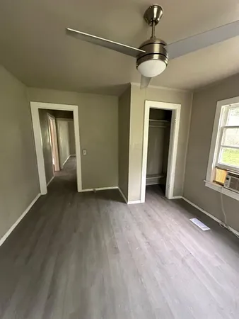 an empty room with a chandelier fan and windows