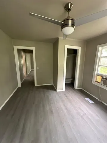 an empty room with a chandelier fan and windows