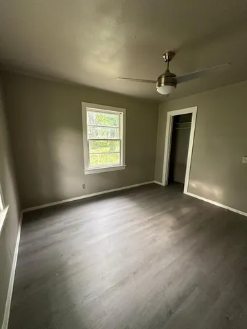 an empty room with windows and fan