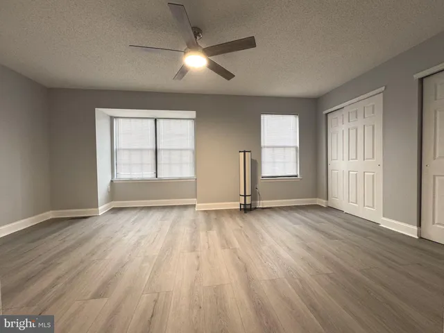an empty room with wooden floor cabinet and windows