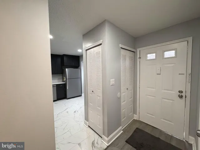 a view of a kitchen with refrigerator and wooden cabinets