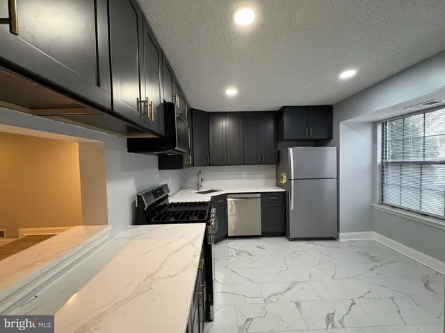 a large white kitchen with lot of cabinets and refrigerator