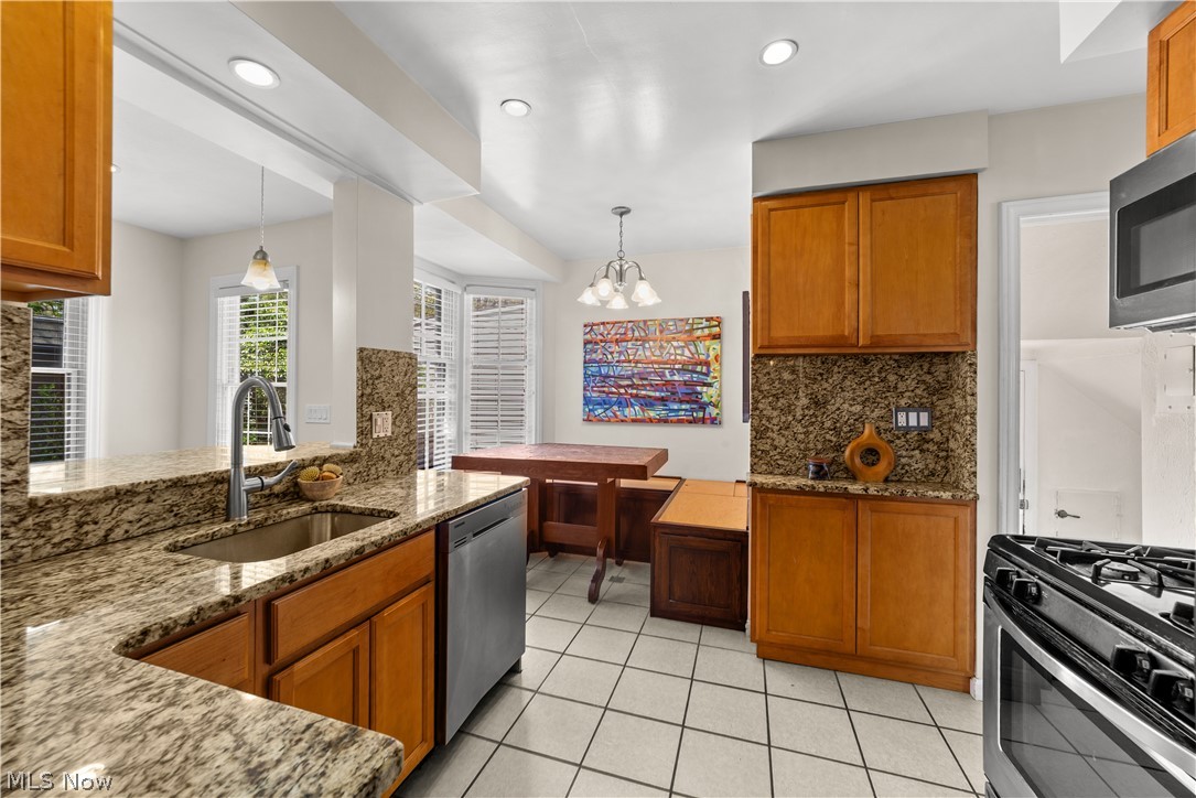 3806 Westwood Road University Heights, OH 44118 - Photo 12 of 41 Kitchen featuring granite countertops, wood cabinetry, tile flooring, a stainless steel sink with a pull-down faucet, and integrated stainless steel appliances
