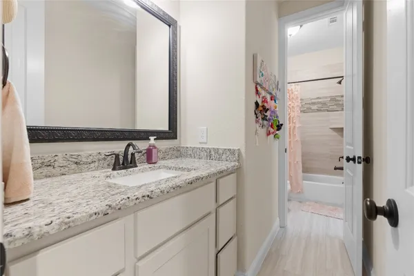 a bathroom with a granite countertop sink a mirror and a shower
