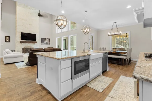a kitchen with kitchen island granite countertop a stove a sink dishwasher a dining table and chairs with wooden floor