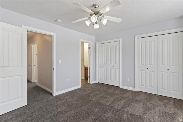 2350 South Highway 89, Unit 4 Perry, UT 84302 - Photo 23 of 30 Unfurnished bedroom featuring multiple closets, dark colored carpet, a ceiling fan, and ensuite bathroom