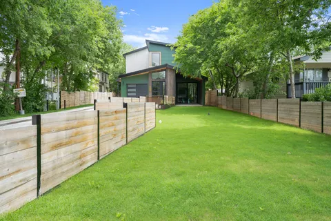 a view of a backyard with wooden fence and a large tree