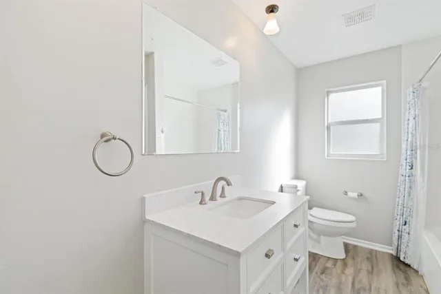 a bathroom with a granite countertop sink a toilet and a mirror