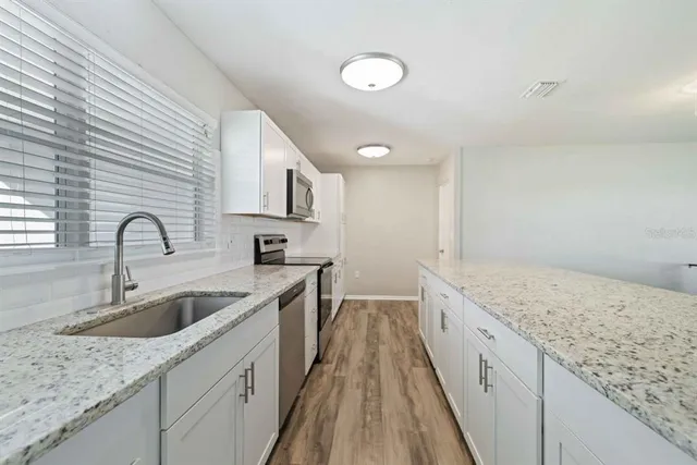 a kitchen with granite countertop a sink and wooden cabinets