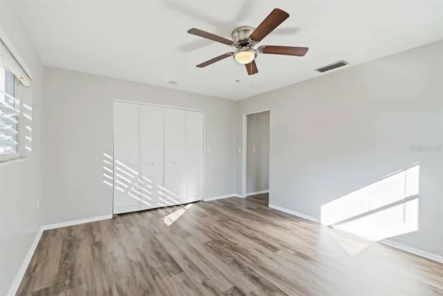 an empty room with wooden floor and windows