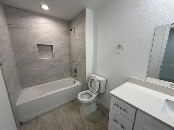 a bathroom with a granite countertop toilet a sink and bathtub
