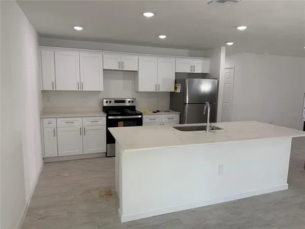 a kitchen with kitchen island a white counter top space cabinets and stainless steel appliances