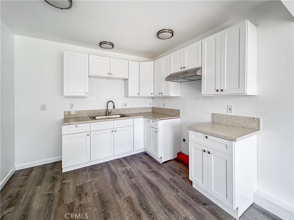 4215 Santa Ana Street, Unit O Huntington Park, CA 90255 - Photo 3 of 10 a kitchen with a sink dishwasher and white cabinets with wooden floor