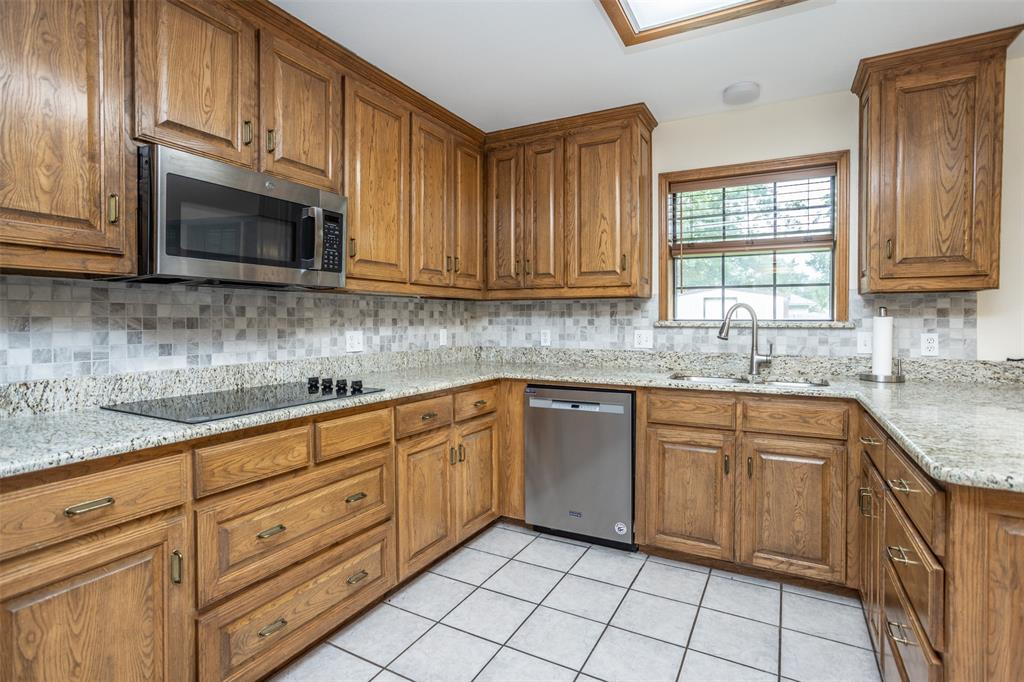292 Old Spanish Trail Valley View, TX 76272 - Photo 12 of 40 Kitchen featuring stainless steel appliances, brown cabinets, decorative backsplash, and light tile patterned flooring