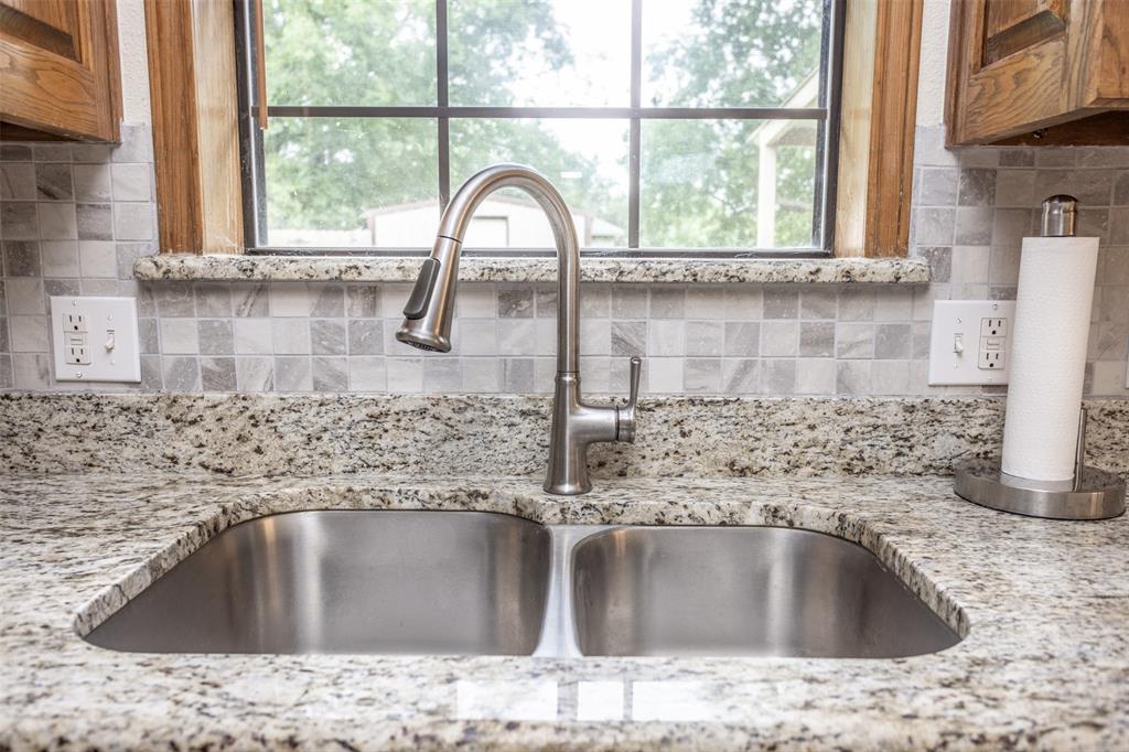 292 Old Spanish Trail Valley View, TX 76272 - Photo 18 of 40 Kitchen view of decorative backsplash, brown cabinetry, and light stone countertops