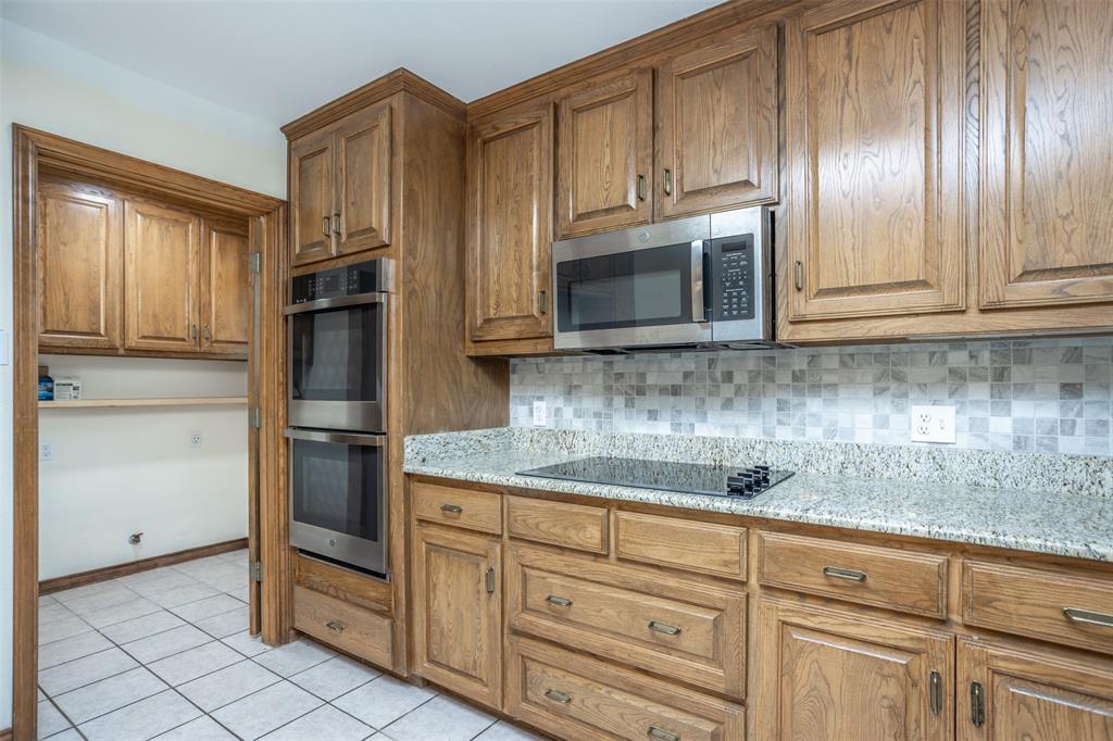 292 Old Spanish Trail Valley View, TX 76272 - Photo 19 of 40 Kitchen with appliances with stainless steel finishes, brown cabinetry, and backsplash