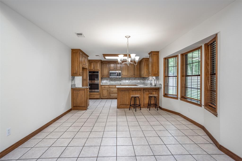 292 Old Spanish Trail Valley View, TX 76272 - Photo 9 of 40 Kitchen with appliances with stainless steel finishes, a chandelier, brown cabinets, backsplash, and a peninsula