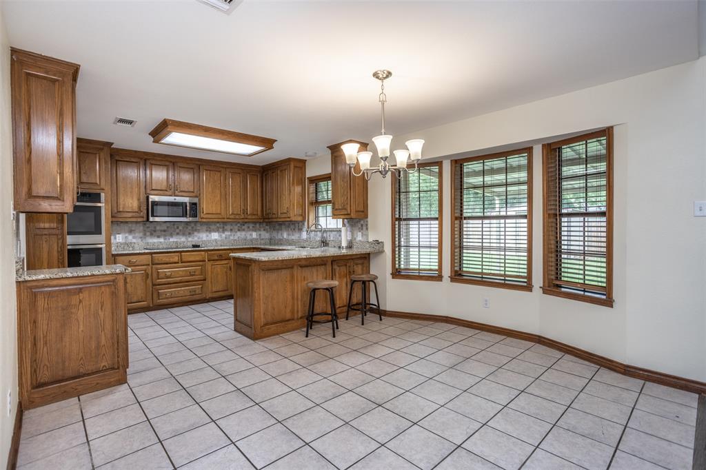 292 Old Spanish Trail Valley View, TX 76272 - Photo 10 of 40 Kitchen featuring appliances with stainless steel finishes, light tile patterned floors, a chandelier, brown cabinetry, and a peninsula