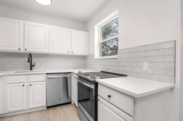 a kitchen with white cabinets stainless steel appliances and sink