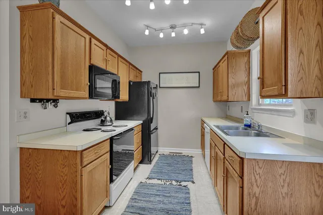 a kitchen with a sink a stove top oven a refrigerator cabinets and furniture