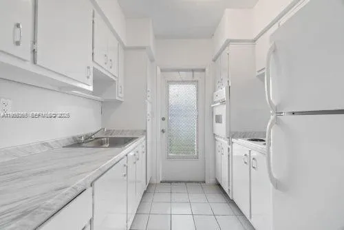 a kitchen with white cabinets and refrigerator