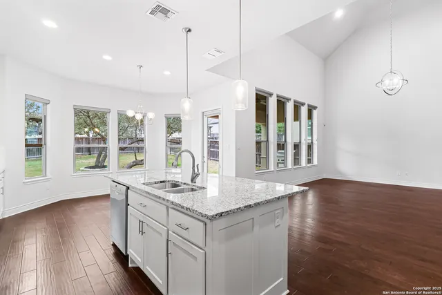 a kitchen with granite countertop a stove a sink a window and wooden floor