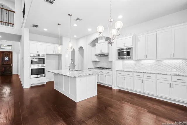 a large kitchen with kitchen island white cabinets and stainless steel appliances