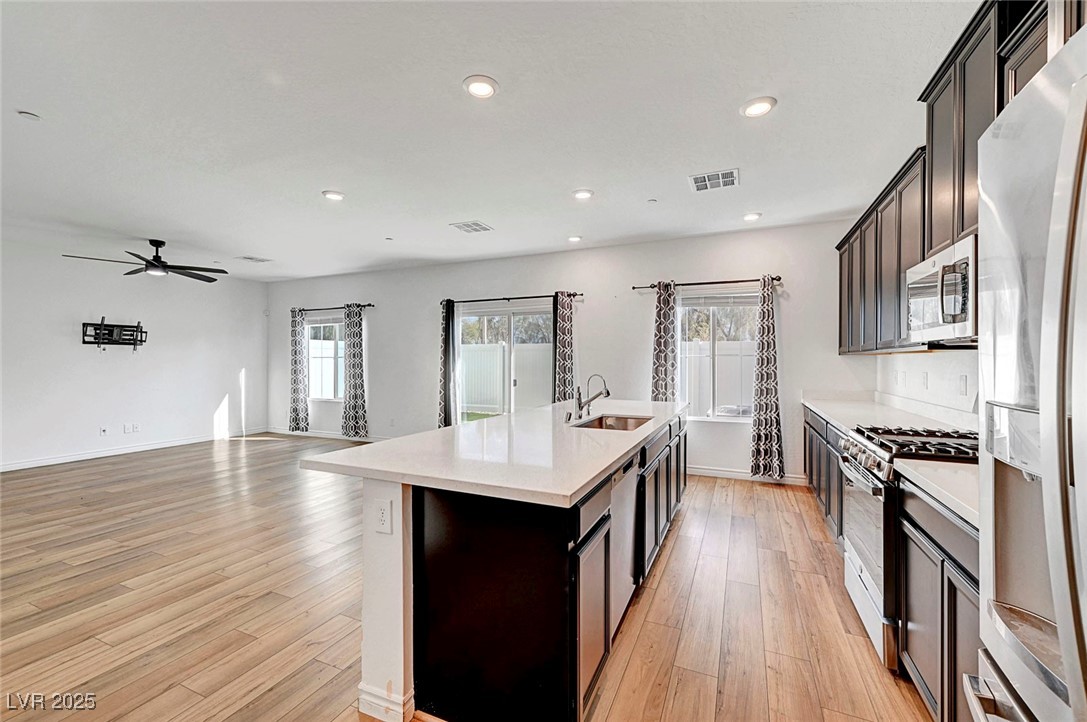 7204 North Decatur Boulevard North Las Vegas, NV 89084 - Photo 19 of 55 Kitchen with light countertops, a kitchen island with sink, stainless steel appliances, a sink, and light wood-style floors