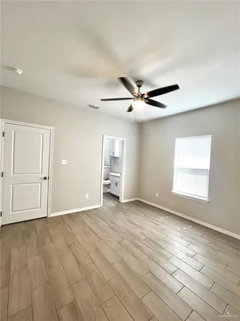 a view of an empty room with window and wooden floor