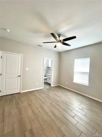 a view of an empty room with window and wooden floor