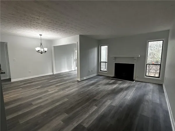 a view of an empty room with window and wooden floor