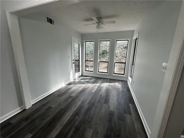 a view of an empty room with wooden floor and a window